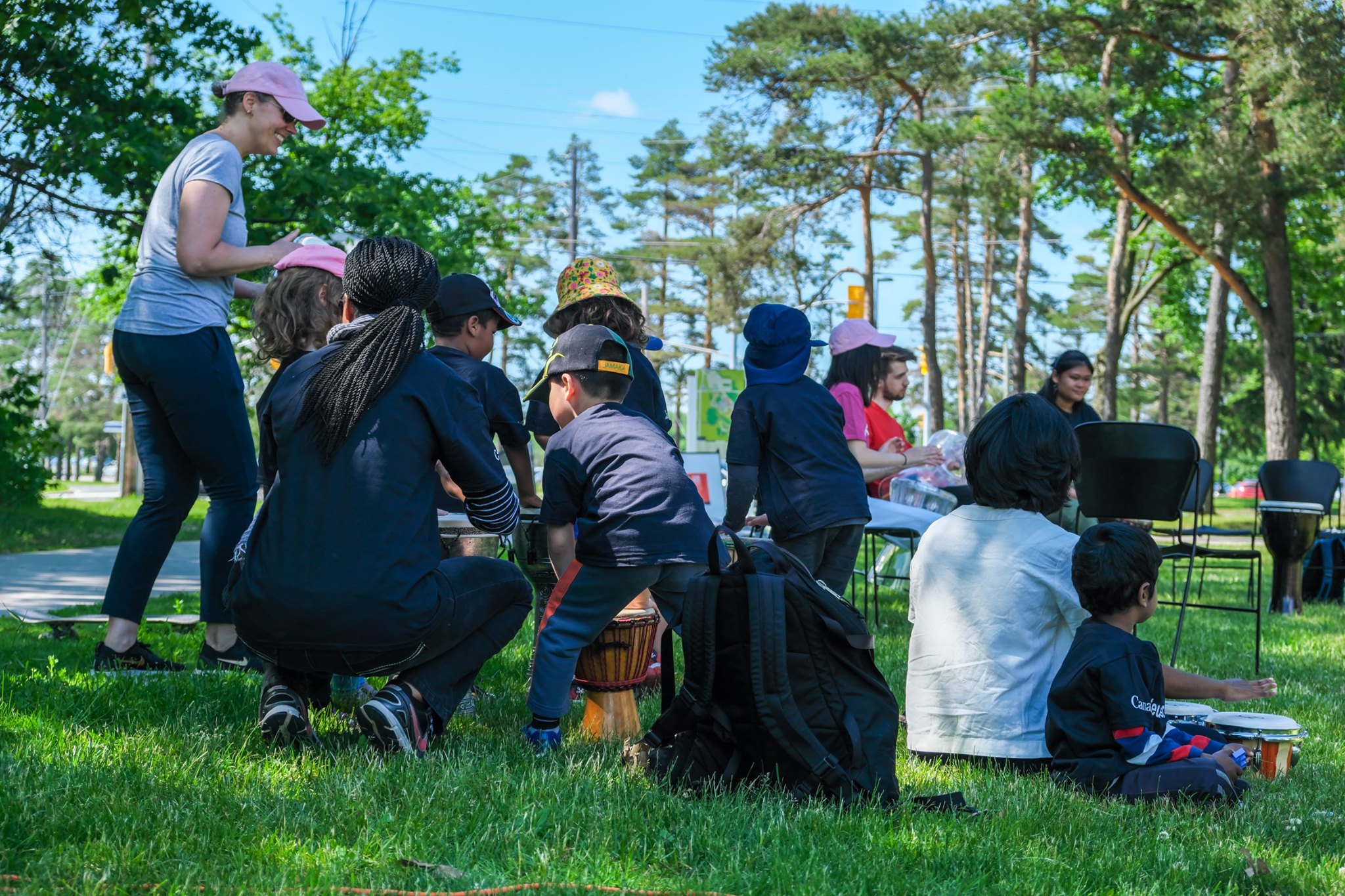 Participants siting on the grass playing various percussion instruments