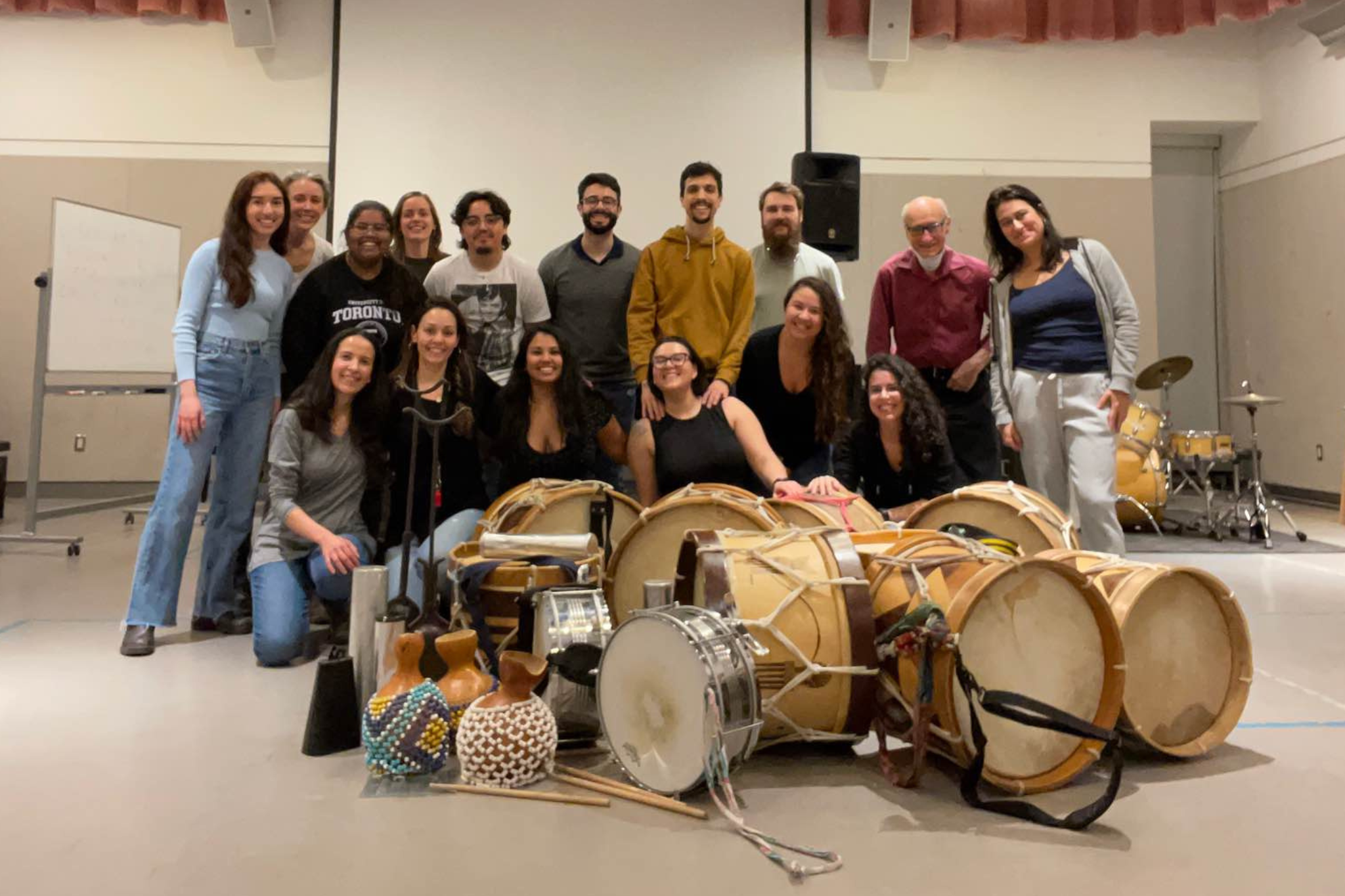 A group photo of a maracatu class with various instruments displayed in the front